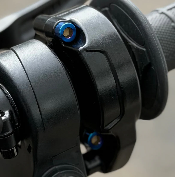 Close-up image of titanium throttle bolts for Surron installed on a throttle grip.