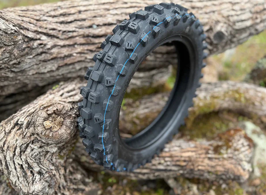 ETM RTR Lite OEM tires displayed on a log, showcasing its rugged design and factory-spec performance features.