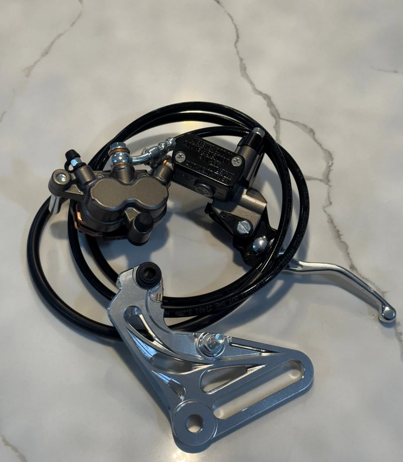 Tuttio Yozma brake kit components including brake caliper, lever, and hose on a marble surface.